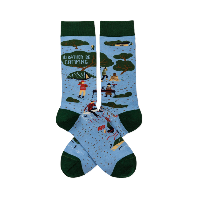 Pair of light blue crew socks with dark green trim. Features 'I'D RATHER BE CAMPING' text, trees, tents, and campers.