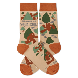 Pair of crew socks in beige, rust orange, and green, patterned with brown Sasquatch, trees, and 