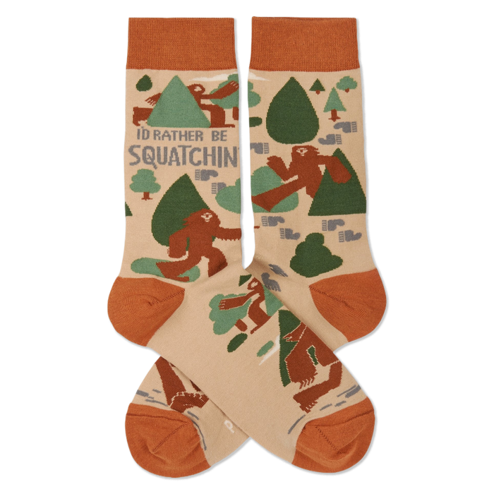 Pair of crew socks in beige, rust orange, and green, patterned with brown Sasquatch, trees, and 