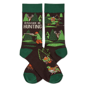 Pair of dark brown crew socks with green cuffs, heels, and toes. Pattern includes trees, deer, and hunters with rifles and bows. Text reads 'I'D RATHER BE HUNTING'.