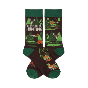 Pair of dark brown crew socks with green cuffs, heels, and toes. Pattern includes trees, deer, and hunters with rifles and bows. Text reads 'I'D RATHER BE HUNTING'.