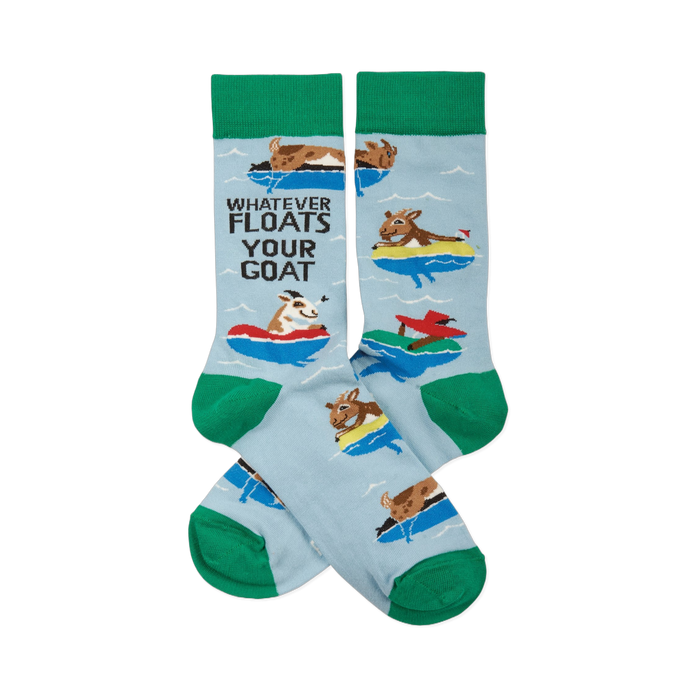 A pair of light blue crew socks with green cuffs, heels, and toes, featuring cartoon goats floating in colorful inner tubes and text.
