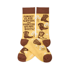 Pair of yellowish-tan crew socks with brown cuffs, heels, and toes. They feature brown cowboy boots, white flowers, and the quote 