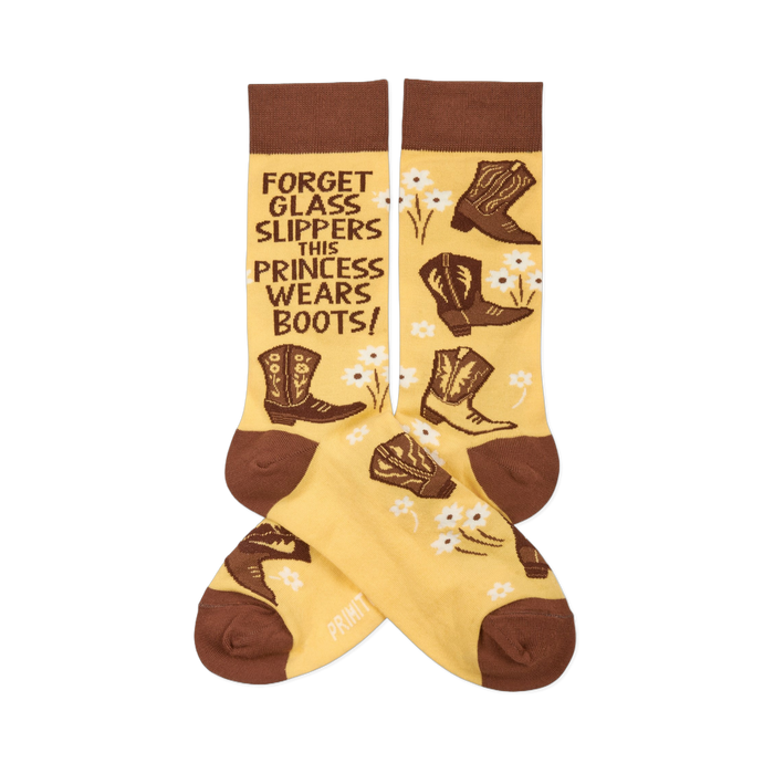 Pair of yellowish-tan crew socks with brown cuffs, heels, and toes. They feature brown cowboy boots, white flowers, and the quote 