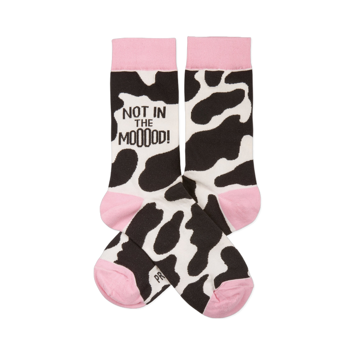 Pair of crew socks with black and white cow print, pink cuffs, heels, and toes. One sock reads 