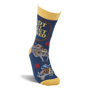 Single dark blue crew sock with yellow accents, shown upright, featuring 'NOT MY FIRST RODEO' text and a bucking bull.