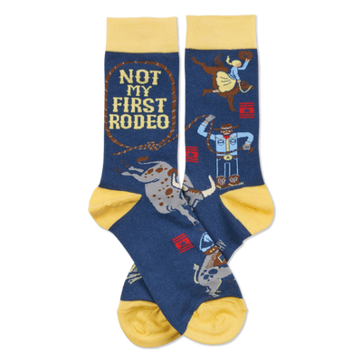 Pair of dark blue crew socks with yellow cuffs, heels, and toes. Design includes cowboys, bulls, and "NOT MY FIRST RODEO" text.