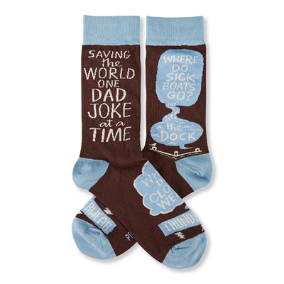 Pair of brown crew socks with light blue cuffs, heels, and toes. White text reads "SAVING THE WORLD ONE DAD JOKE at a TIME" and "WHERE DO SICK BOATS GO? the DOCK" inside speech bubbles.