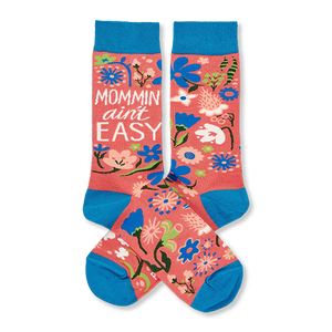 Two coral pink crew socks with blue cuffs, heels, and toes, featuring a colorful floral pattern and 