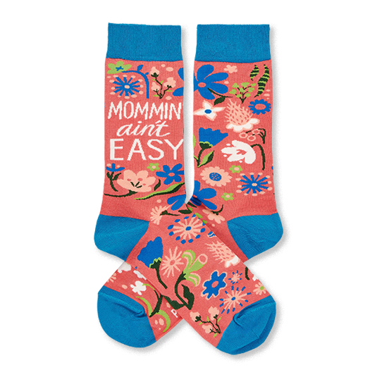 Two coral pink crew socks with blue cuffs, heels, and toes, featuring a colorful floral pattern and 