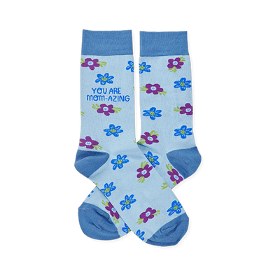 Pair of light blue crew socks with scattered blue and purple flowers. One sock reads "YOU ARE MOM-AZING" in green text.