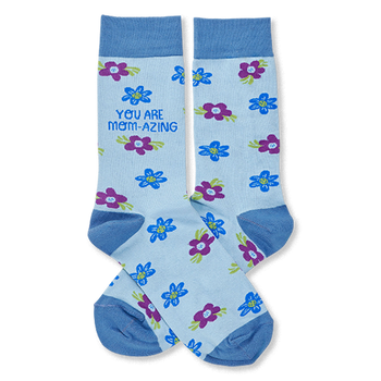 Pair of light blue crew socks with scattered blue and purple flowers. One sock reads "YOU ARE MOM-AZING" in green text.