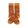 Pair of crew socks in rust orange with yellow cuffs, heels, and toes. Features scattered yellow, teal, and blue flowers. One sock reads 'FUN FACT... I DON'T CARE' in blue and teal text.