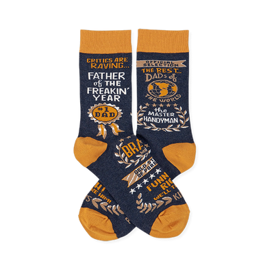 Pair of navy blue crew socks with mustard yellow accents, covered in gold and white text like 'Father Of The Year' and 'Master Handyman'.