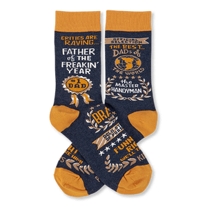 Pair of navy blue crew socks with mustard yellow accents, covered in gold and white text like 'Father Of The Year' and 'Master Handyman'.