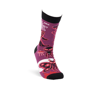 Single purple crew sock shown at an angle, featuring Mothman, alien, and UFO patterns with black cuff and toe.