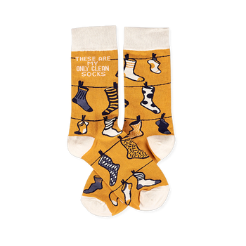 Pair of mustard yellow crew socks with off-white cuffs, heels, and toes, featuring a clothesline pattern with various small socks and the phrase 'THESE ARE MY ONLY CLEAN SOCKS'.