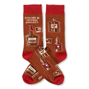 Pair of crew socks in brown with red cuffs, heels, and toes. Patterned with whiskey bottles, glasses, and text 'I'D RATHER BE SIPPING WHISKEY'.