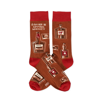 Pair of crew socks in brown with red cuffs, heels, and toes. Patterned with whiskey bottles, glasses, and text 'I'D RATHER BE SIPPING WHISKEY'.