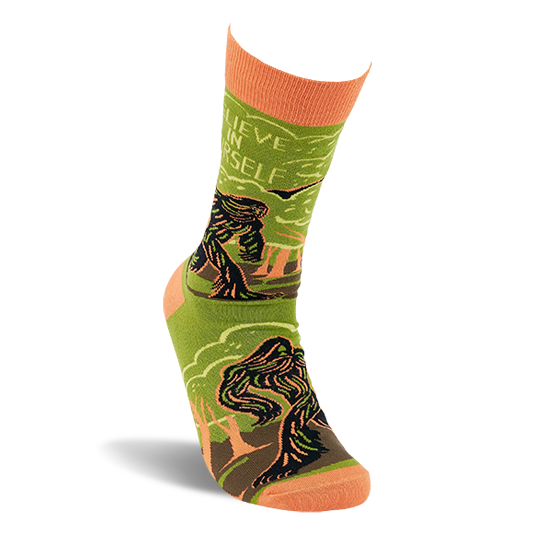 A single olive green and orange Bigfoot crew sock standing upright, showing the creature, forest, and 'Believe In Yourself' text.
