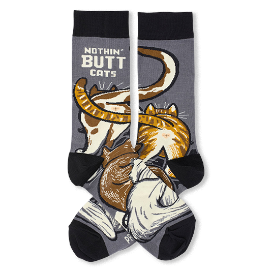 A pair of crew socks with a dark gray body, black cuffs, heels, and toes, featuring a graphic print of three cats and the text 'NOTHIN' BUTT CATS'.