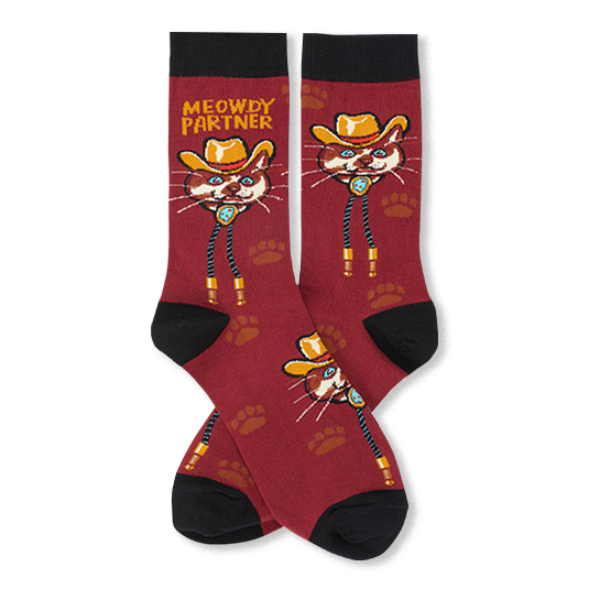 Pair of burgundy crew socks with black cuffs, heels, and toes featuring a cartoon cat dressed as a cowboy wearing a tan hat and blue bolo tie. One sock displays the phrase "MEOWDY PARTNER" in yellow above the cat, while the other shows the cat without text. The socks are decorated with subtle brown paw prints, and the product is shown with one pair laid flat and another sock overlapping in front.