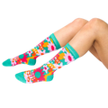 A person's legs, bent at the knees, wearing the green, pink, orange, and yellow floral 'Mother Of The Freakin' Year' crew socks on a white background.