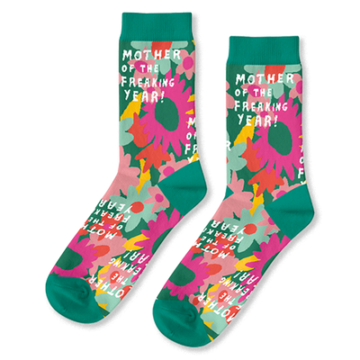 Pair of crew socks with pink, orange, and yellow flowers on a green background and teal cuffs, heels, toes.