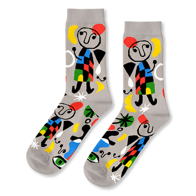 A pair of light grey crew socks with a vibrant abstract pattern, featuring black-outlined figures, colorful shapes, and green eyes.