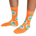 A person wearing a pair of orange crew socks featuring a ranch dressing bottle pattern, standing on a white background.