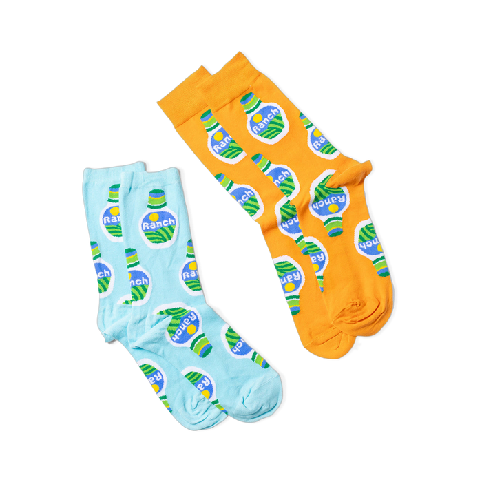 Two pairs of socks, one orange and one light blue, both with a ranch dressing bottle pattern, laid flat on black.