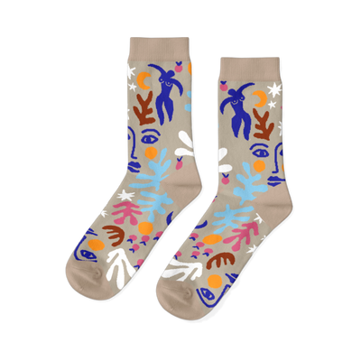 Pair of crew socks with an abstract Matisse-inspired pattern featuring blue figures, faces, stars, and leaves on a tan background.