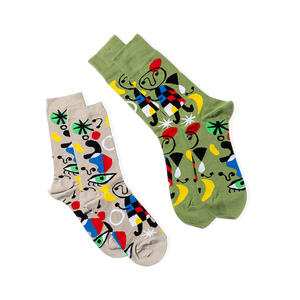Two pairs of abstract art crew socks. One pair is olive green, the other light beige, both with colorful art patterns.