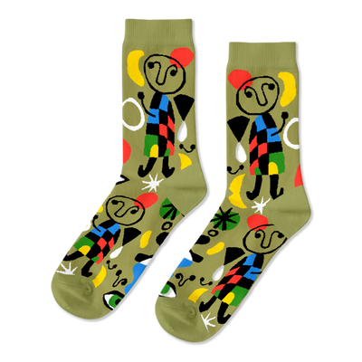 Pair of olive green crew socks with abstract art pattern, featuring stick figures, red stars, yellow moons, and colorful geometric shapes.