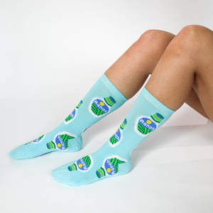 A person's legs are shown wearing light blue crew socks with a ranch dressing bottle pattern on a white background.