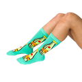 A person's lower legs and feet, wearing the aqua Top Chica bottle crew socks, sitting on a white surface.