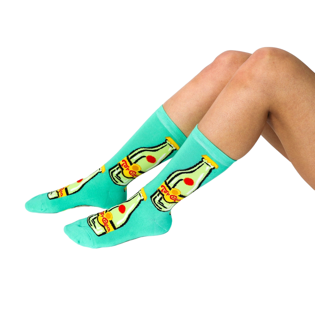 A person's lower legs and feet, wearing the aqua Top Chica bottle crew socks, sitting on a white surface.