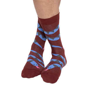 A person's bare legs wearing reddish-brown snake pattern crew socks, with ankles crossed, against a plain background.