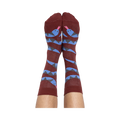 A person's bare legs wearing reddish-brown snake pattern crew socks, shown from the soles up, against a plain background.