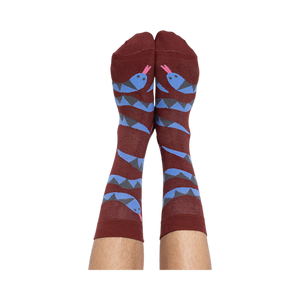 A person's bare legs wearing reddish-brown snake pattern crew socks, shown from the soles up, against a plain background.
