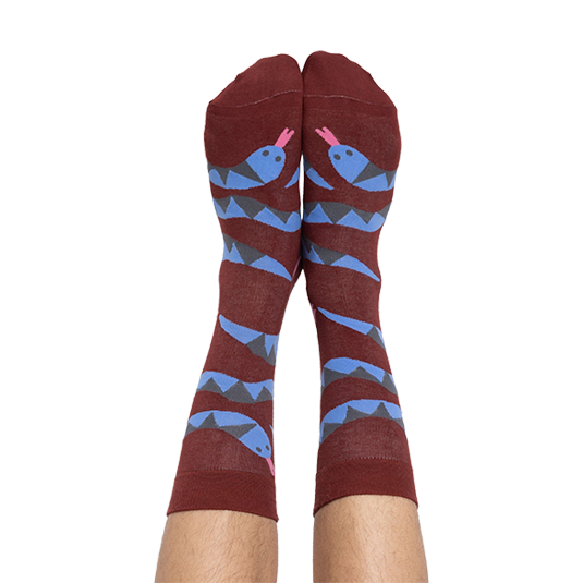 A person's bare legs wearing reddish-brown snake pattern crew socks, shown from the soles up, against a plain background.