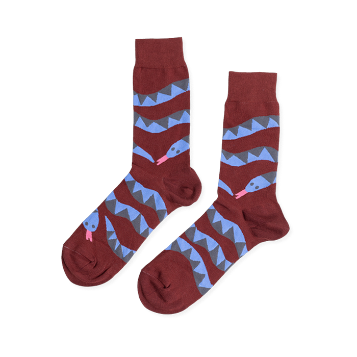 Pair of reddish-brown crew socks laid flat, featuring coiled blue and gray snake patterns with pink tongues, on a white background.