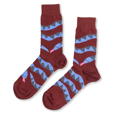Pair of reddish-brown crew socks laid flat, featuring coiled blue and gray snake patterns with pink tongues, on a white background.