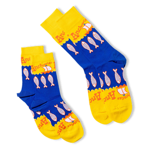 Two pairs of anchovy crew socks, one lying flat and one folded, showing the blue and yellow design with fish and sailboats.