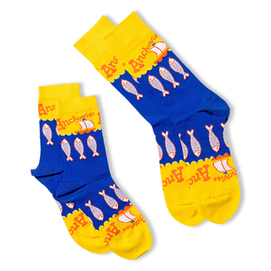 Two pairs of anchovy crew socks, one lying flat and one folded, showing the blue and yellow design with fish and sailboats.