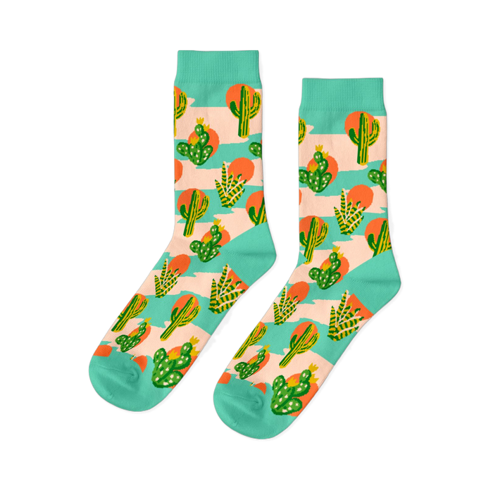 Pair of crew socks with a desert theme. Features green saguaro and prickly pear cacti, orange suns, on a peach-pink and mint green striped background. }}