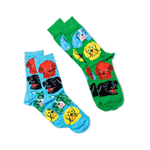 Two pairs of crew socks: one green with colorful dog faces, one light blue with colorful dog faces.