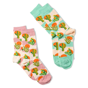 Two pairs of crew socks with Southwest cactus patterns. One pair features lavender accents, the other has blue-green accents.