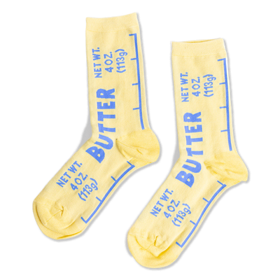 Pair of yellow crew socks designed like butter sticks, featuring blue 'BUTTER' text and net weight measurements.