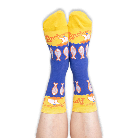 Person wearing blue and yellow anchovy socks with their feet pointed up against a black background, showing the toe design.